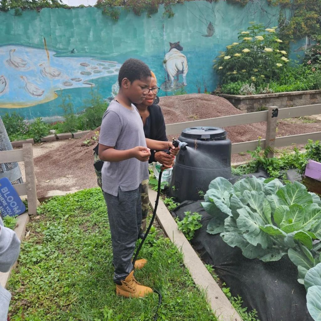 Instructor showing child how to water plants during Literacy and More event.
